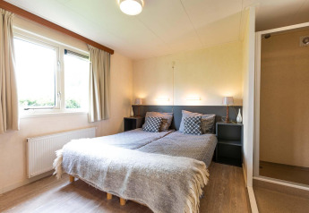 Camera nella casa vacanze di EuroParcs Noordwijkse Duinen con due letti singoli e ampia finestra luminosa.