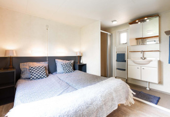 Helles Schlafzimmer mit zwei Einzelbetten und eigenem Bad in einem Ferienhaus im EuroParcs Noordwijkse Duinen, Niederlande.