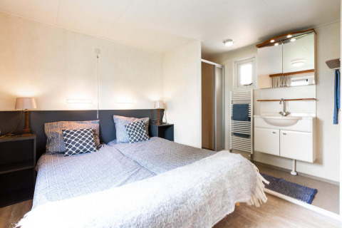 Lichte slaapkamer met twee aparte bedden en badkamer in vakantiehuis bij EuroParcs Noordwijkse Duinen, Nederland.