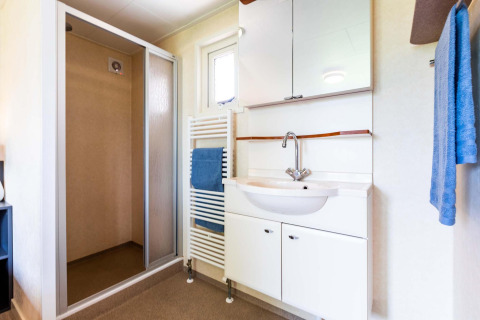 Bagno moderno con doccia, lavandino e asciugamani blu in casa vacanza a EuroParcs Noordwijkse Duinen, Paesi Bassi.