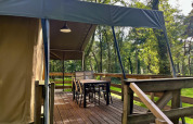 Safaritent Summer Lodge bij Beerze Bulten in Nederland met overdekt houten terras en tuinstoelen.