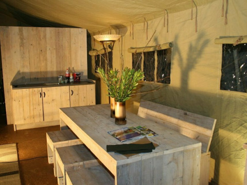 Interieur van de safaritent Summer Lodge bij Beerze Bulten, Nederland, met houten meubels en gezellige sfeer.