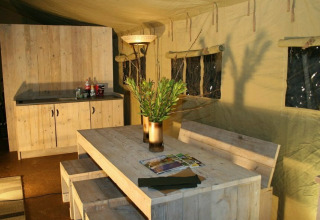 Interieur van de safaritent Summer Lodge bij Beerze Bulten, Nederland, met houten meubels en gezellige sfeer.