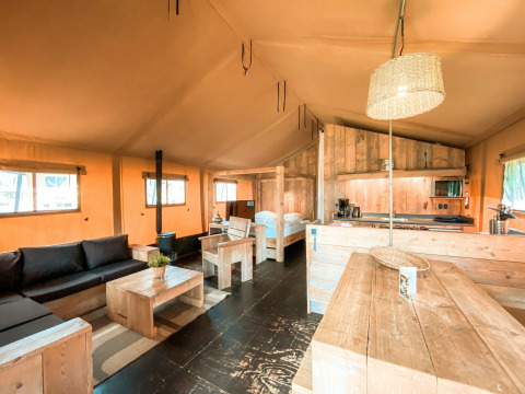 Interior de la tienda safari Summer Lodge en Beerze Bulten, Países Bajos, con muebles de madera y luz natural.
