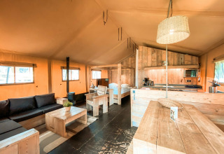 Interior de la tienda safari Summer Lodge en Beerze Bulten, Países Bajos, con muebles de madera y luz natural.