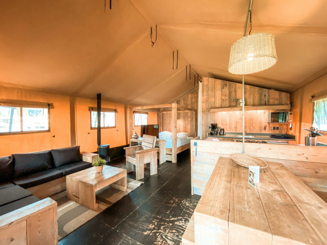 Interieur van safaritent Summer Lodge bij Beerze Bulten in Nederland, met houten meubels en warme sfeer.