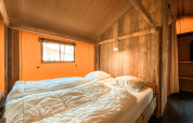 Gezellige slaapkamer in een safaritent, Summer Lodge, op Beerze Bulten in Nederland met houten wanden.