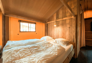 Acogedor dormitorio en una tienda safari llamada Summer Lodge en Beerze Bulten, Países Bajos, con paredes de madera.