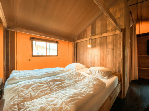 Knusse slaapkamer in een safaritent genaamd Summer Lodge bij Beerze Bulten in Nederland, met houten muren.