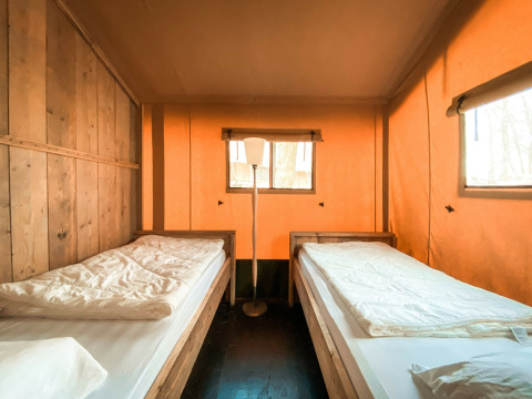 Interieur van safari tent Summer Lodge bij Beerze Bulten in Nederland, met twee aparte bedden en warme tinten.