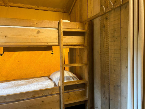 Houten stapelbed met witte lakens in een safaritent van Summer Lodge, Beerze Bulten, Nederland.