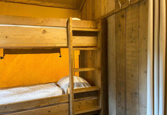 Letto a castello in legno con lenzuola bianche in una tenda safari al Summer Lodge, Beerze Bulten, Paesi Bassi.