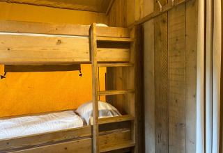 Holzetagenbett mit weißer Bettwäsche in einem Safarizelt bei Summer Lodge, Beerze Bulten, Niederlande.