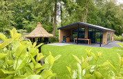 Moderne familielodge med store vinduer og veranda i grøn skovhave, De Thijmse Berg, Holland.