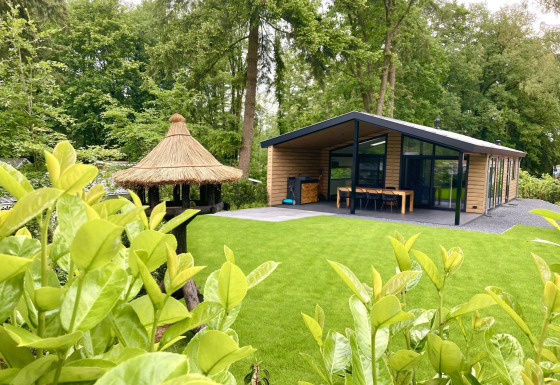 Moderne familielodge med store vinduer og veranda i grøn skovhave, De Thijmse Berg, Holland.