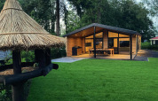 Familieindkvartering i træ, Family Lodge Deluxe, De Thijmse Berg, Holland, omgivet af grøn have.