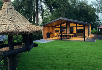 Family Lodge Deluxe a De Thijmse Berg nei Paesi Bassi, chalet moderno in legno con prato verde.