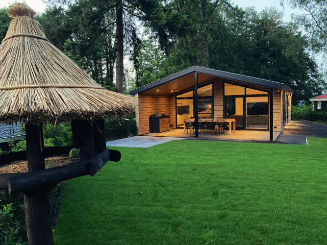 Modernes Familien-Lodge Deluxe bei De Thijmse Berg, Niederlande, mit Terrasse und grüner Rasenfläche.