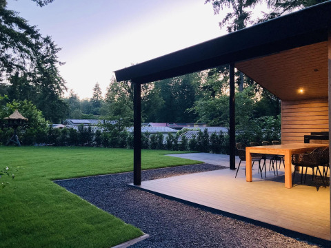 Eethoek op het terras bij Family Lodge Deluxe op De Thijmse Berg in Nederland, omgeven door groen en bomen.