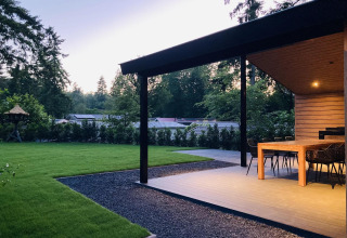 Außenterrasse mit Essbereich der Family Lodge Deluxe im De Thijmse Berg, Niederlande, umgeben von Bäumen.