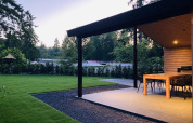 Terraza con comedor en Family Lodge Deluxe en De Thijmse Berg, Países Bajos, rodeada de césped y árboles.