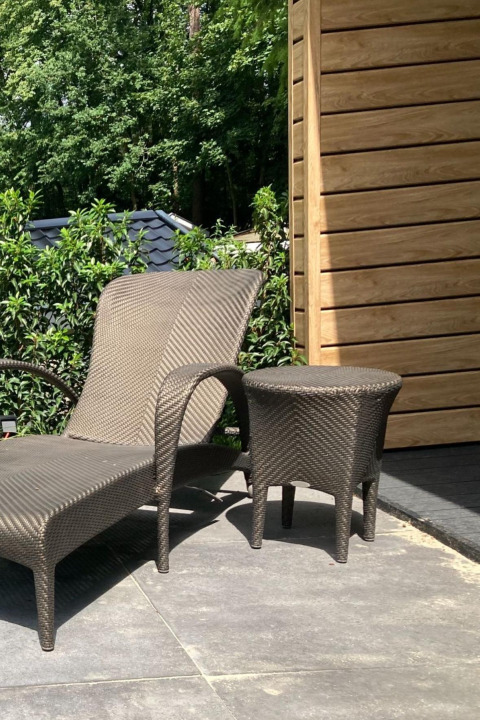 Zonnig terras aan Family Lodge Deluxe, De Thijmse Berg, Nederland, met ligzetel en tafeltje.