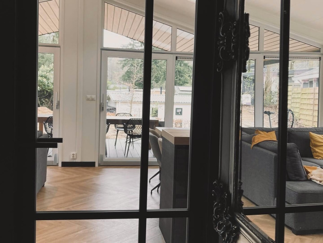 Vue à travers une porte sur le salon du Family Lodge Deluxe à De Thijmse Berg, aux Pays-Bas, avec une déco moderne.