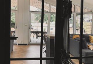 Blick auf ein modernes Wohnzimmer mit großen Fenstern im Family Lodge Deluxe in De Thijmse Berg, Niederlande.