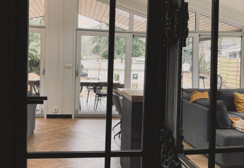 Vue à travers une porte sur le salon du Family Lodge Deluxe à De Thijmse Berg, aux Pays-Bas, avec une déco moderne.