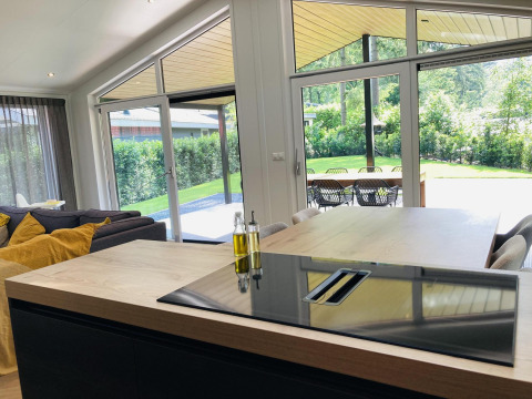 Lodge moderna con cocina y área de comedor, grandes ventanales y vistas al jardín en De Thijmse Berg, Países Bajos.