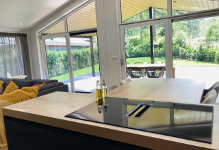 Lodge moderna con cocina y área de comedor, grandes ventanales y vistas al jardín en De Thijmse Berg, Países Bajos.
