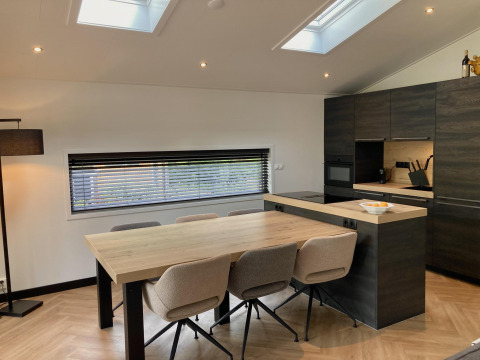Moderne spise- og køkkenområde i Family Lodge Deluxe på De Thijmse Berg, Holland, med stort bord og ovenlys.