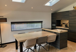 Moderne spise- og køkkenområde i Family Lodge Deluxe på De Thijmse Berg, Holland, med stort bord og ovenlys.