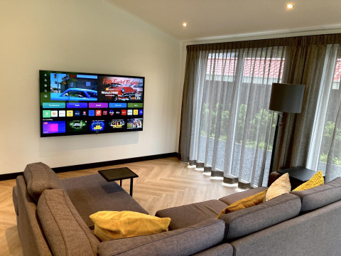 Sala moderna en Family Lodge Deluxe en De Thijmse Berg, Países Bajos, con sofá, televisor y grandes ventanales.
