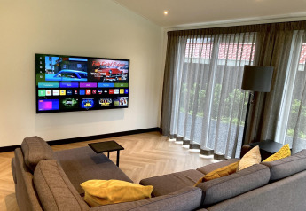 Sala moderna en Family Lodge Deluxe en De Thijmse Berg, Países Bajos, con sofá, televisor y grandes ventanales.