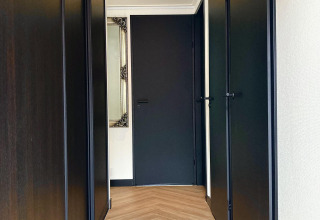 Pasillo de Family Lodge Deluxe en De Thijmse Berg, Países Bajos, con puertas oscuras, espejo y suelo de madera.