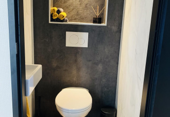 Bagno moderno al Family Lodge Deluxe di De Thijmse Berg, Paesi Bassi, con pareti scure e mensola integrata.