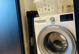 Wasmachine met een wasmand bovenop in Family Lodge Deluxe bij De Thijmse Berg, Nederland.