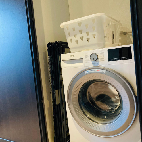 Waschmaschine mit einem Wäschekorb obenauf in der Family Lodge Deluxe bei De Thijmse Berg, Niederlande.