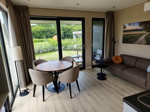 Sala moderna en Holiday villa Amalia 2 con mesa de comedor, sofá y vista al jardín en Hofparken Wiltershaar.