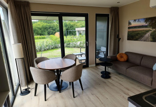 Sala moderna en Holiday villa Amalia 2 con mesa de comedor, sofá y vista al jardín en Hofparken Wiltershaar.