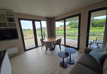 Lys stue i Holiday villa Amalia 2 med store vinduer og udsigt over haven ved Hofparken Wiltershaar.