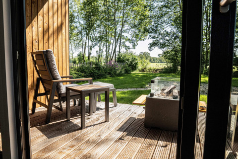 Terraza de madera con silla y mesa en Holiday villa Amalia 2, vista al jardín en los Países Bajos.