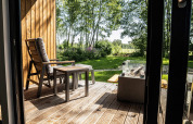 Træterrasse med stol og bord på Holiday villa Amalia 2 med udsigt til have og natur i Holland.