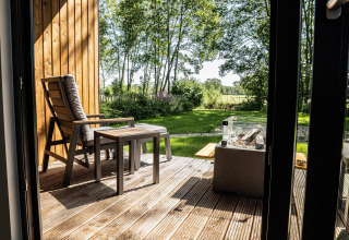 Terraza de madera con silla y mesa en Holiday villa Amalia 2, vista al jardín en los Países Bajos.