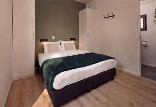 Dormitorio moderno con cama doble y baño privado en la Holiday villa Amalia 2 en Hofparken Wiltershaar.