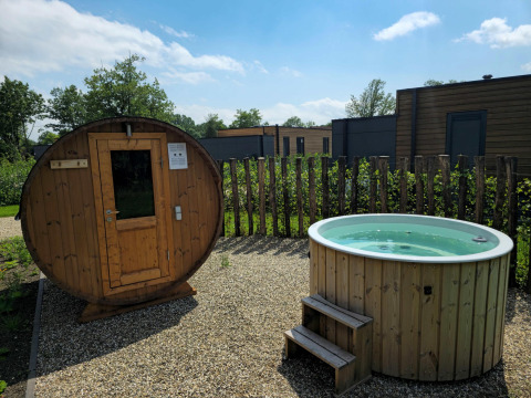 Sauna al aire libre y jacuzzi en una villa vacacional de Hofparken Wiltershaar, Países Bajos, en un día soleado.
