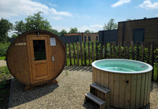 Sauna al aire libre y jacuzzi en una villa vacacional de Hofparken Wiltershaar, Países Bajos, en un día soleado.