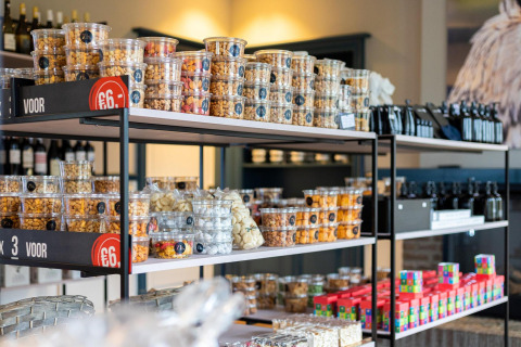 Foto van een rek in een lodge met uiteenlopende noten en snacks in doorzichtige bakjes te koop.