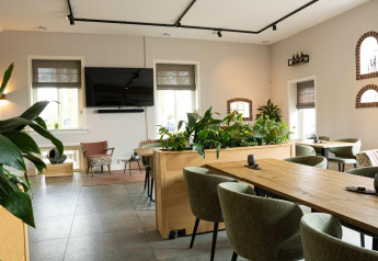 Moderne lounge met planten en televisie in Holiday villa Amalia, Hofparken Wiltershaar, Nederland.